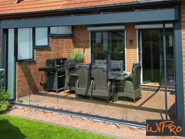 Terrassenüberdachung mit Glasschiebetüren, Sitzgruppe und Grill am Haus