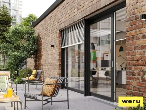 Moderne Terrassentür aus Aluminium in Backsteinfassade mit gemütlicher Sitzgruppe im Garten.