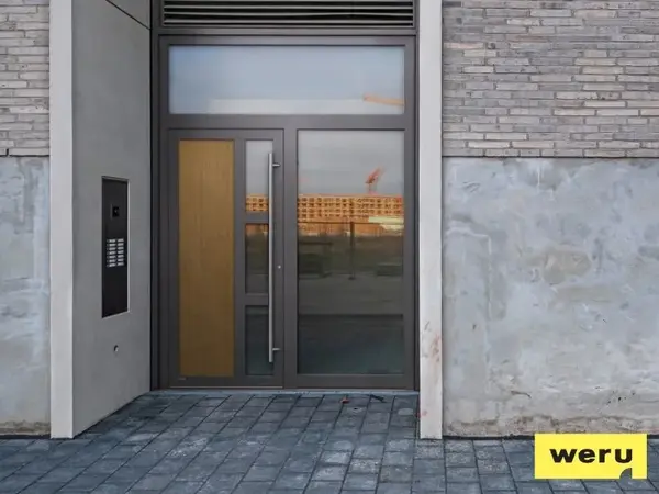 Moderne Haustür aus Glas und Aluminium mit Seitenteil und großer Griffstange, Weru Logo unten.