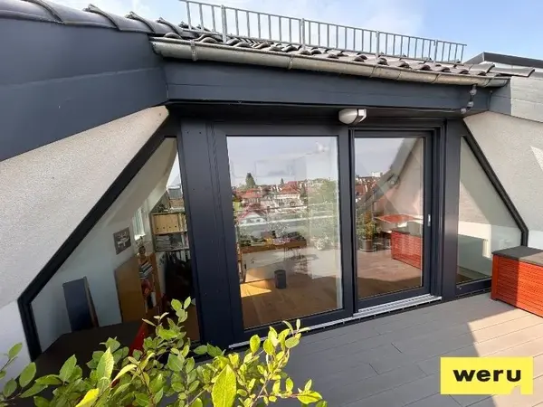 Moderne Terrassentür aus Glas mit schwarzem Rahmen in einer Dachwohnung mit Ausblick.