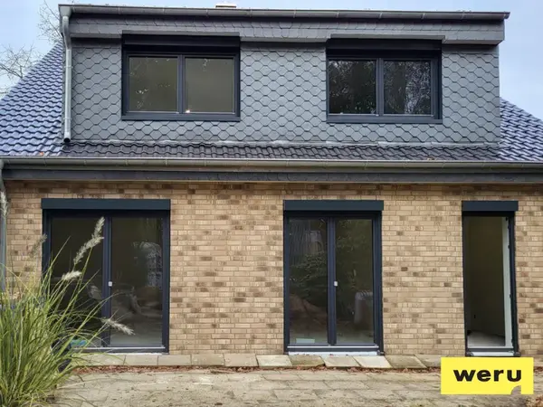 Hausfassade mit neuen schwarzen Fenstern und Türen, Dachgaube modernisiert
