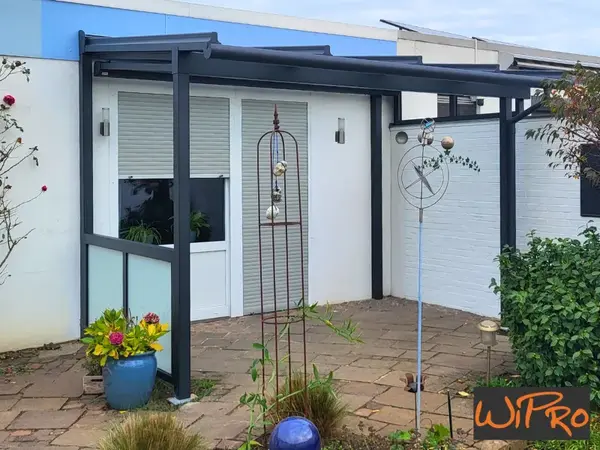 Terrassenüberdachung aus Aluminium am Haus mit Rollläden und Gartenpflanzen